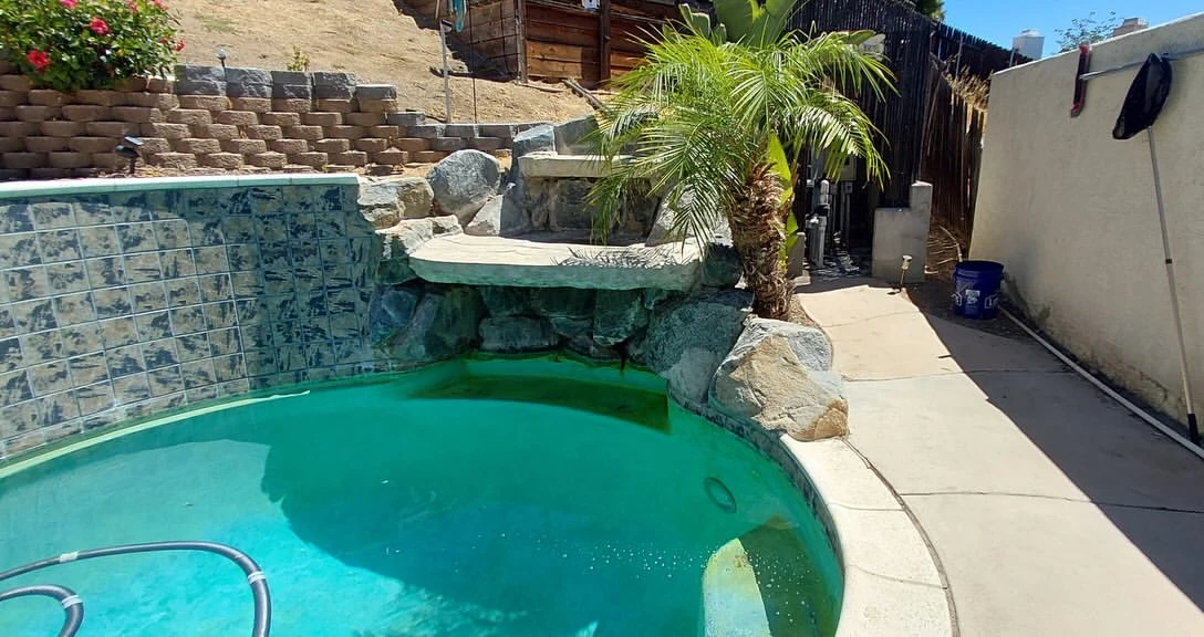 Spa with a rock waterfall and cloudy water before cleaning